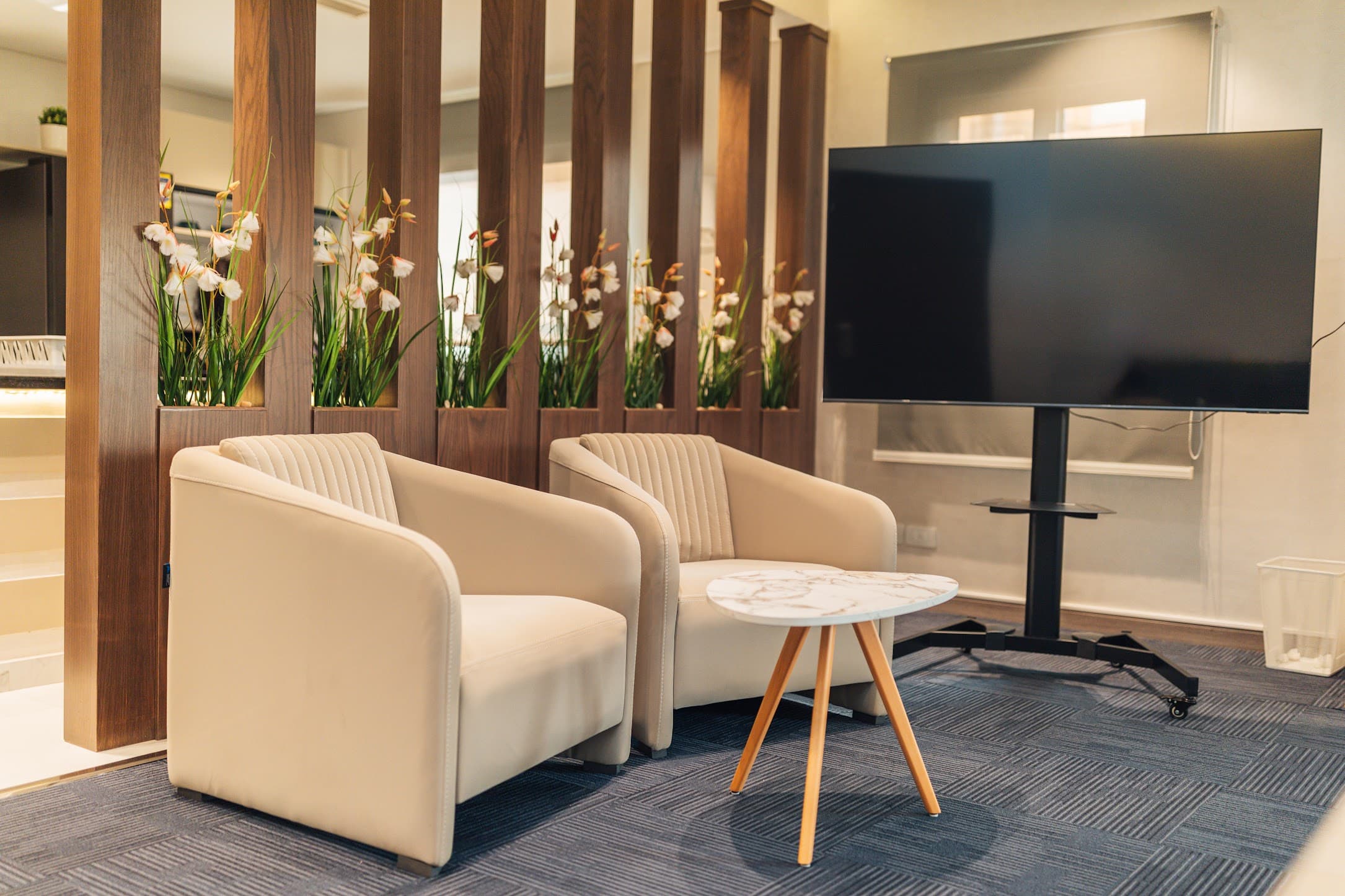 Lounge area at the office — cream chairs, flowers, calm.